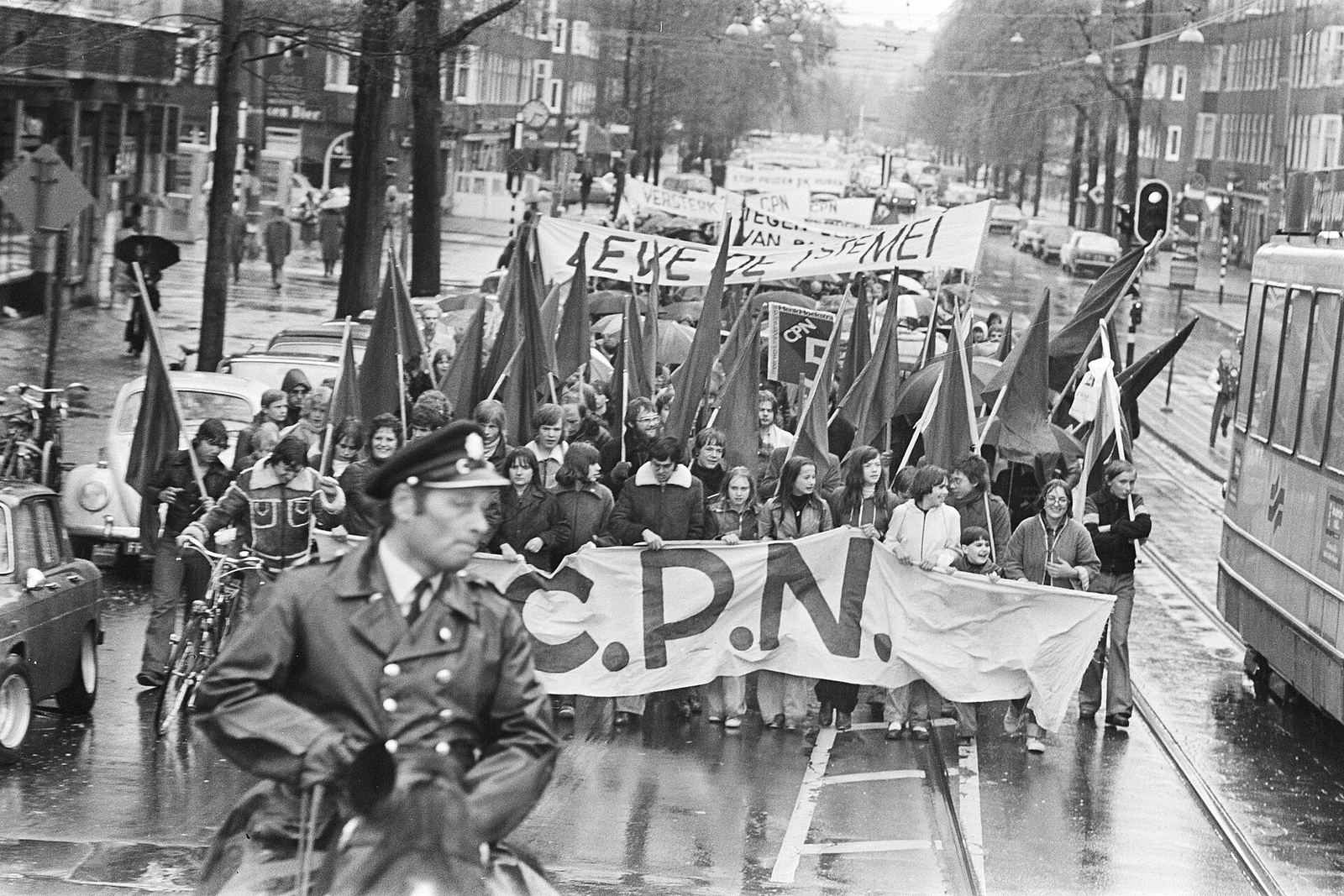 CPN May Day demonstration in the rain, with a large C.P.N. banner and red flags