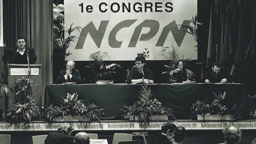 The first congress of the NCPN: a speaker at the lectern, the congress presidium at the table under a large NCPN banner