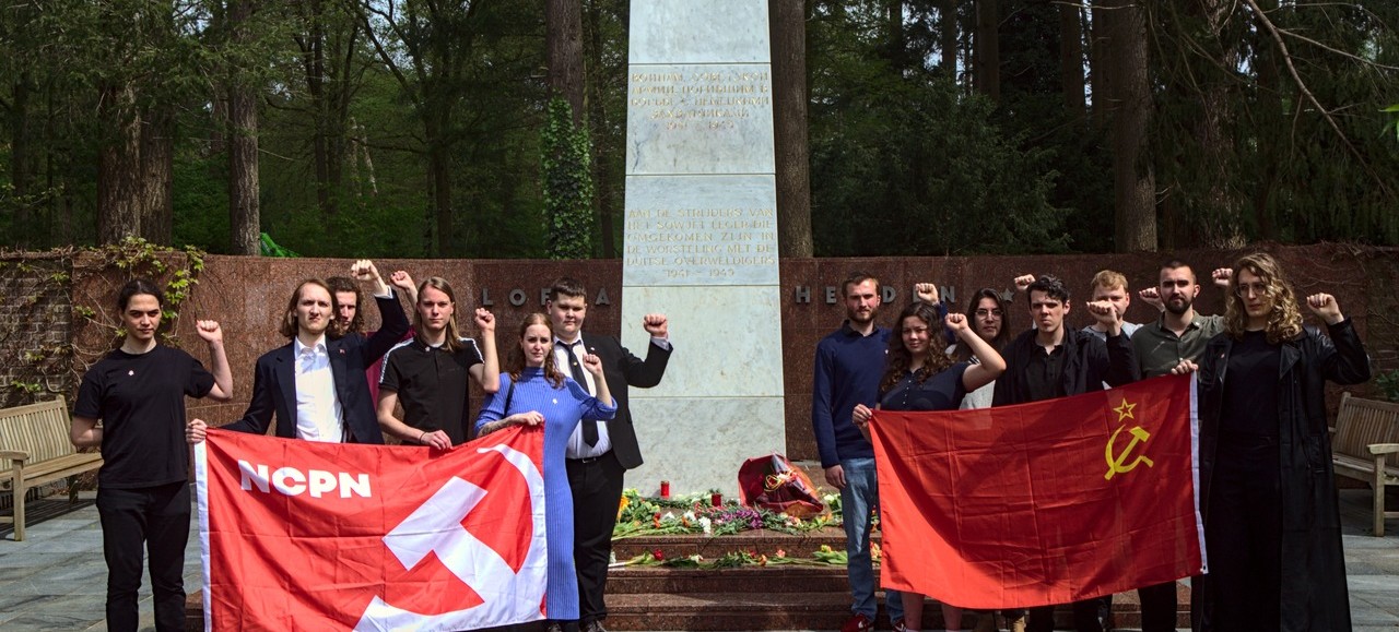 Kameraden met geheven vuist en rode vlaggen bij het monument op het Sovjet Ereveld in Leusden