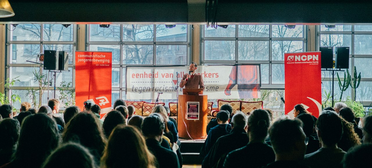 A full hall listens to a speech at the commemoration of the February Strike
