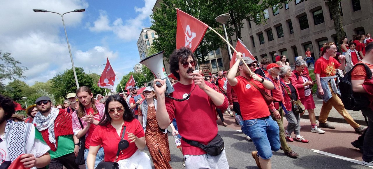 Demonstrators in red shirts with a megaphone and flags at the Red Line march in The Hague