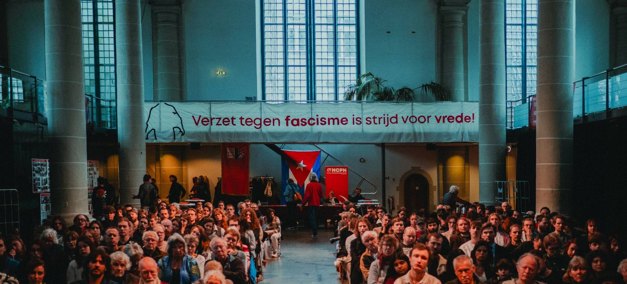 Volle zaal onder het spandoek Verzet tegen fascisme is strijd voor vrede