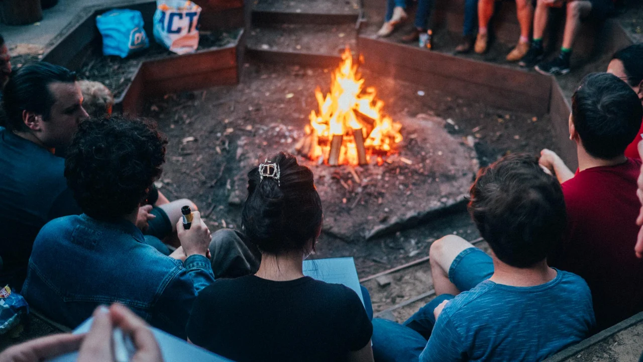 Jonge communisten zitten rond het kampvuur voor een pubquiz, tijdens het vijfde zomerkamp van de CJB.